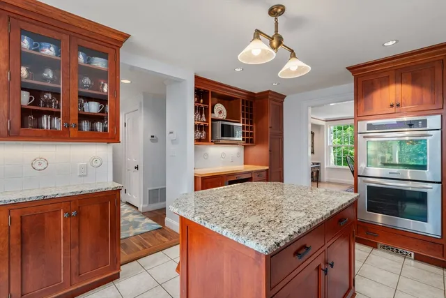 a kitchen with kitchen island granite countertop wooden cabinets a stove and a sink