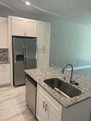 a kitchen with granite countertop a sink and refrigerator