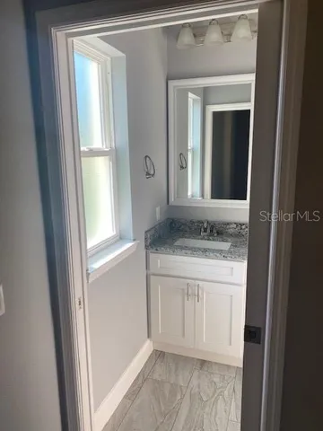 a bathroom with a granite countertop sink and a mirror