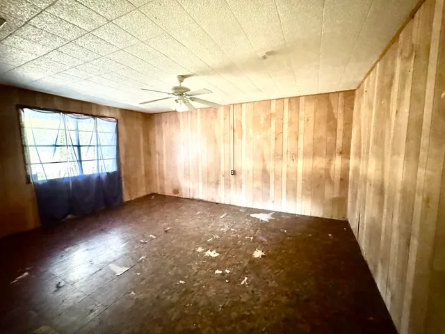 en empty room with windows and ceiling fan