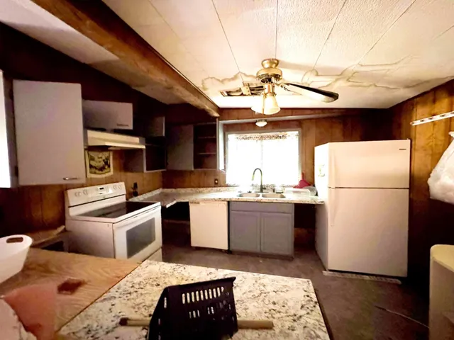a kitchen with a refrigerator a stove a sink dishwasher and a dining table with wooden floor