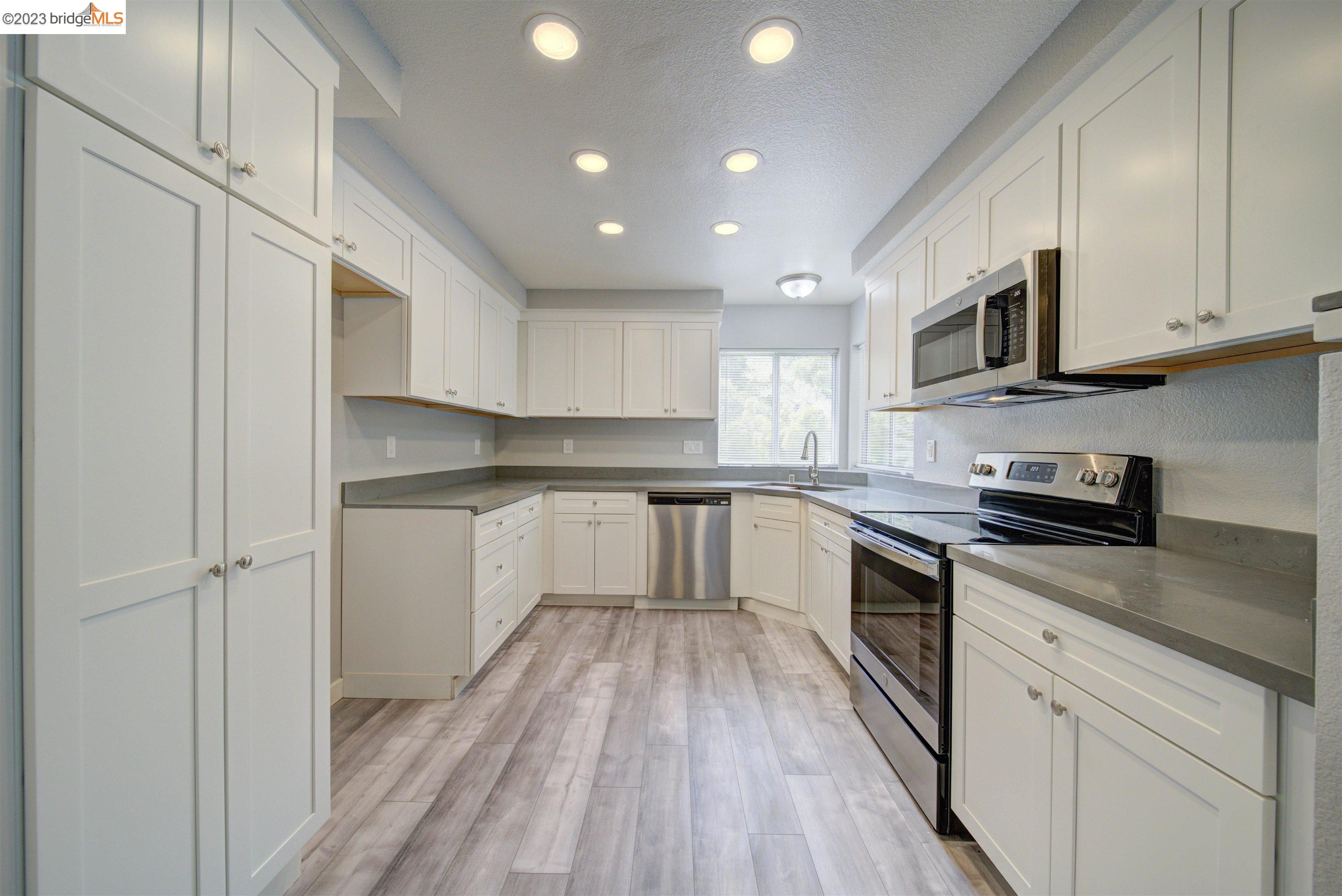 a kitchen with granite countertop a sink cabinets stainless steel appliances and a counter space