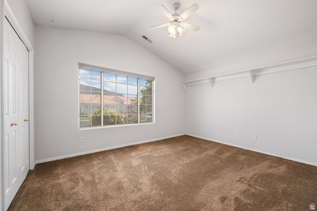 39 North Valley View Drive, Unit 51 St. George, UT 84770 - Photo 21 of 25 Vaulted ceiling room featuring a large multi-pane window, ceiling fan with integrated lighting, built-in shelving, plush brown carpet, and bifold closet doors