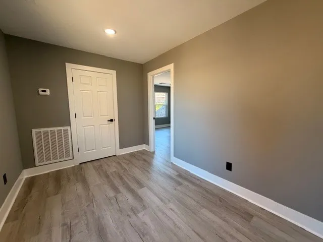 an empty room with wooden floor and closet area