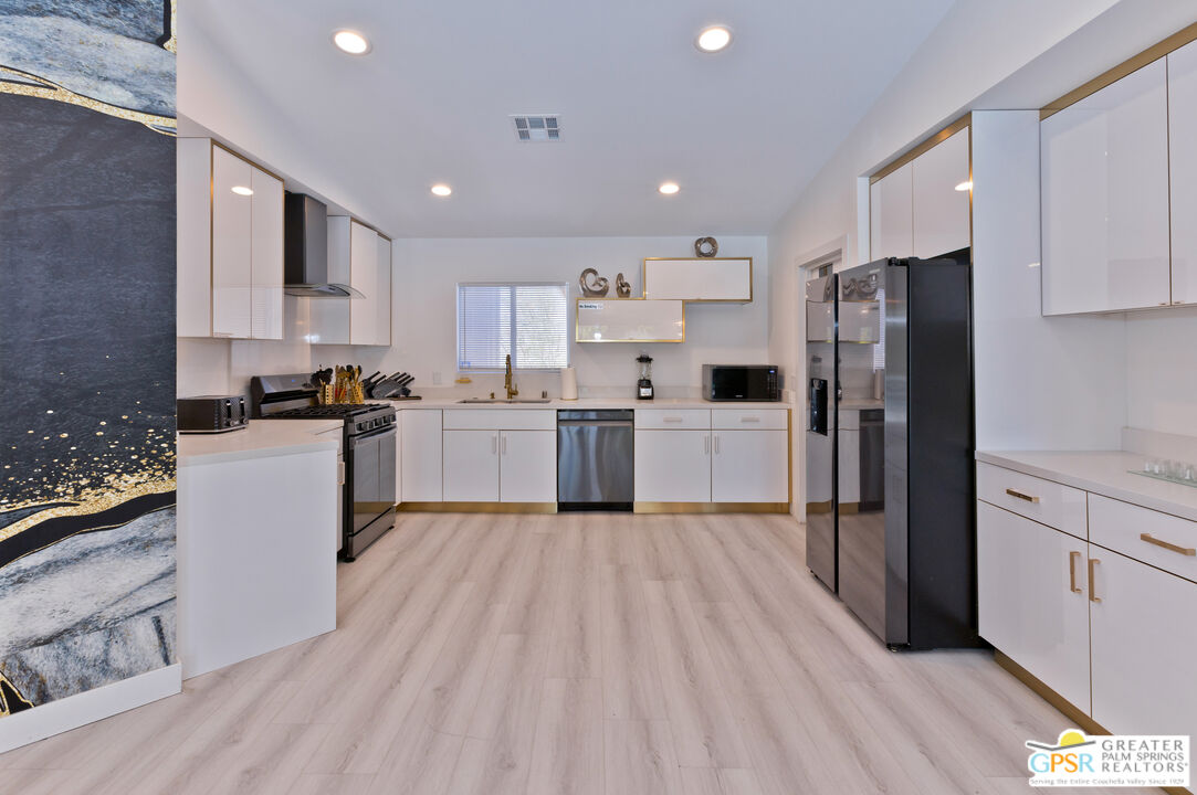 12800 Miracle Hill Road Desert Hot Springs, CA 92240 - Photo 21 of 51 a kitchen with stainless steel appliances granite countertop a refrigerator a stove top oven a sink and cabinets