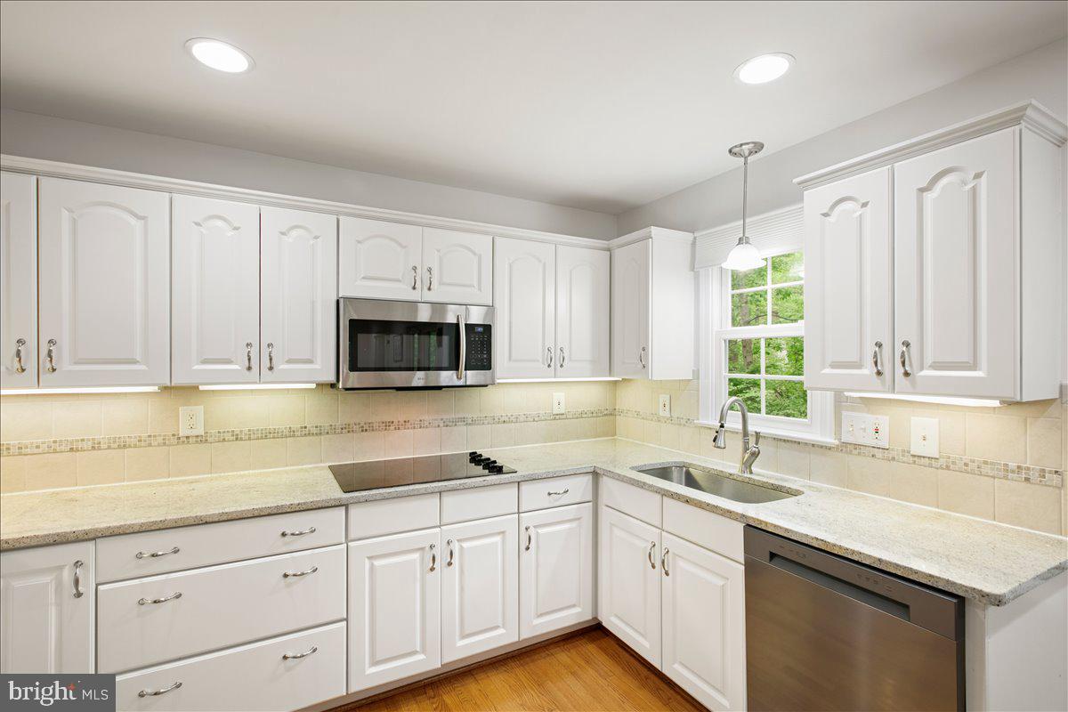 10741 Midsummer Drive Reston, VA 20191 - Photo 29 of 53 a kitchen with granite countertop white cabinets white stainless steel appliances a sink and a window