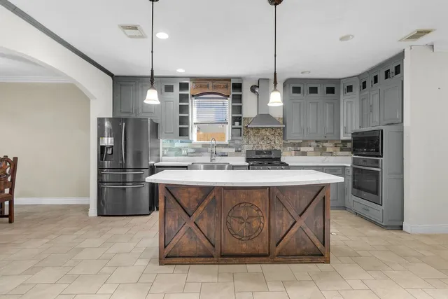 a kitchen with kitchen island a stove a refrigerator a sink and chairs