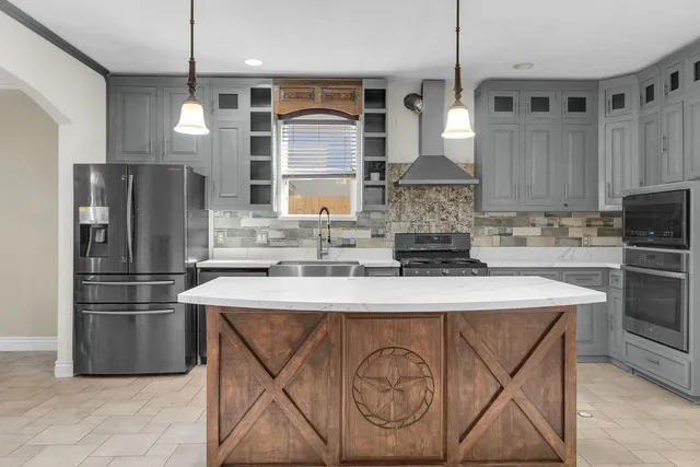 a kitchen with stainless steel appliances granite countertop a sink a stove a refrigerator and island with wooden floor