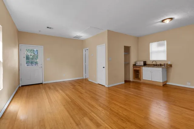 a view of a kitchen with wooden floor electronic appliances and window