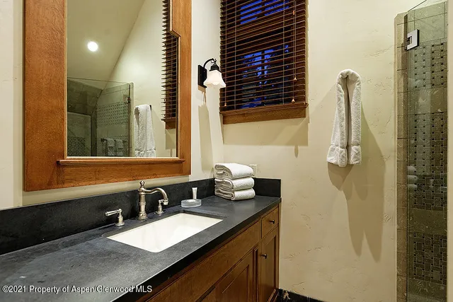 a bathroom with a granite countertop sink a mirror and shower