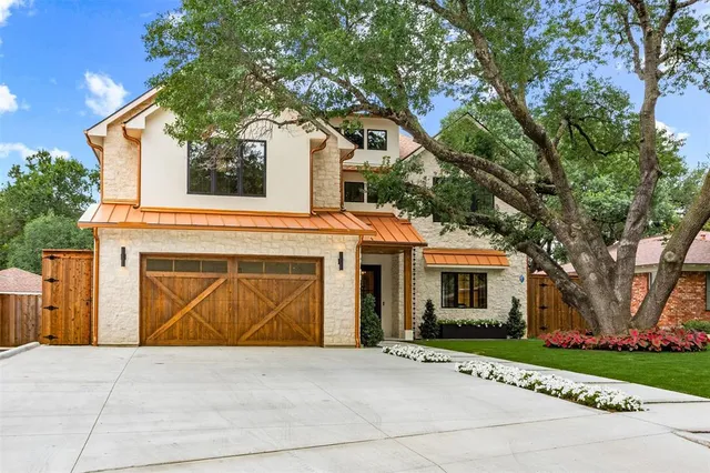 a front view of a house with a garden and trees