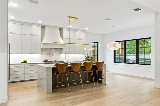 a kitchen with stainless steel appliances granite countertop a stove a sink a oven a dining table and chairs with wooden floor