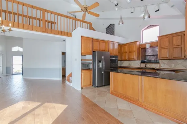 a large kitchen with stainless steel appliances kitchen island granite countertop a refrigerator a stove and a sink with wooden floor