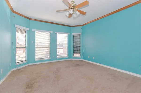 an empty room with windows and ceiling fan