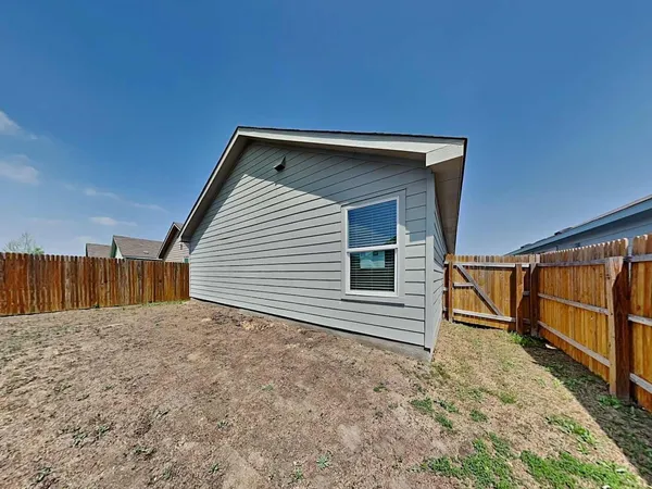 a view of backyard with small cabin and wooden fence