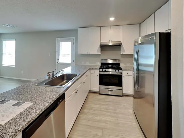 a kitchen with granite countertop kitchen island stainless steel appliances a refrigerator sink stove microwave and cabinets