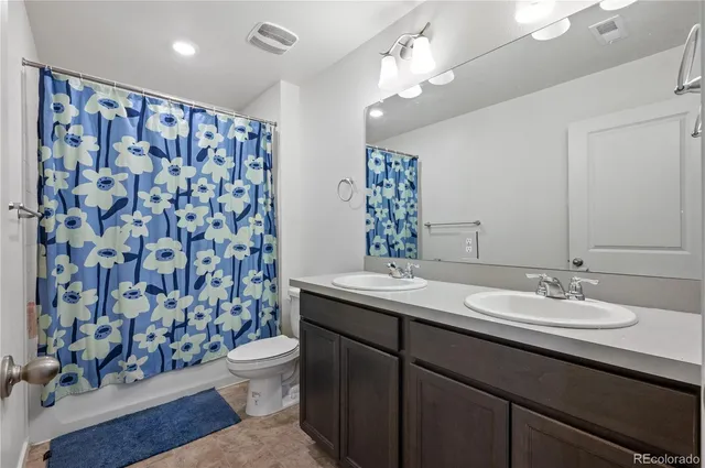 a bathroom with a double vanity sink toilet and a mirror