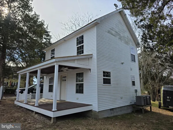 a view of house with a small yard and large tree