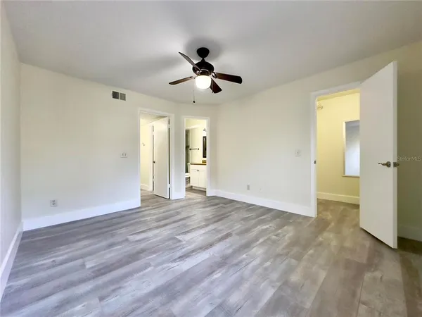 an empty room with wooden floor and a ceiling fan