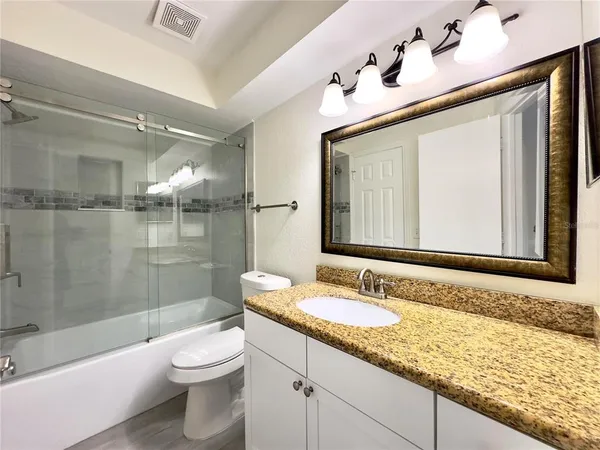 a bathroom with a granite countertop sink toilet and shower