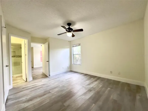 an empty room with wooden floor and ceiling fan