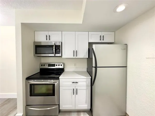 a kitchen with a refrigerator sink and white cabinets