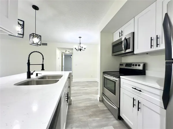 a kitchen with stainless steel appliances granite countertop a sink a stove and a refrigerator