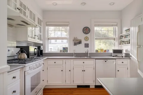 a kitchen with granite countertop white cabinets and window