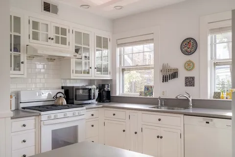 a kitchen with stainless steel appliances white cabinets and a window