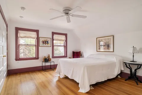 a bedroom with a bed couches and wooden floor