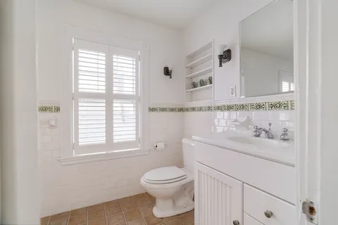 a bathroom with a toilet a sink a vanity and a window