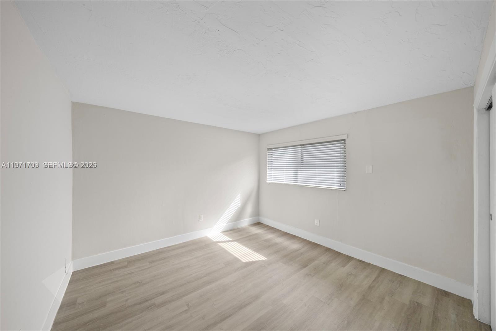 1330 West 29th Street, Unit 39 Hialeah, FL 33012 - Photo 12 of 17 an empty room with wooden floor and windows
