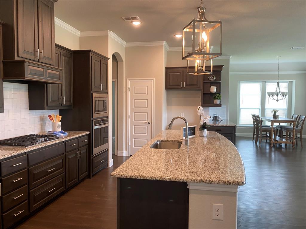 209 Johnson Street Granbury, TX 76048 - Photo 15 of 40 Kitchen featuring sink, tasteful backsplash, stainless steel appliances, dark hardwood / wood-style floors, and an island with sink