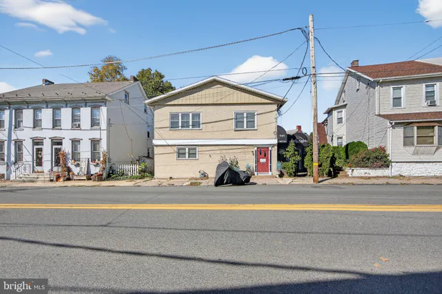 a front view of a building with a garden and entryway