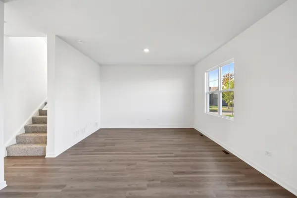a view of an empty room with wooden floor and stairs