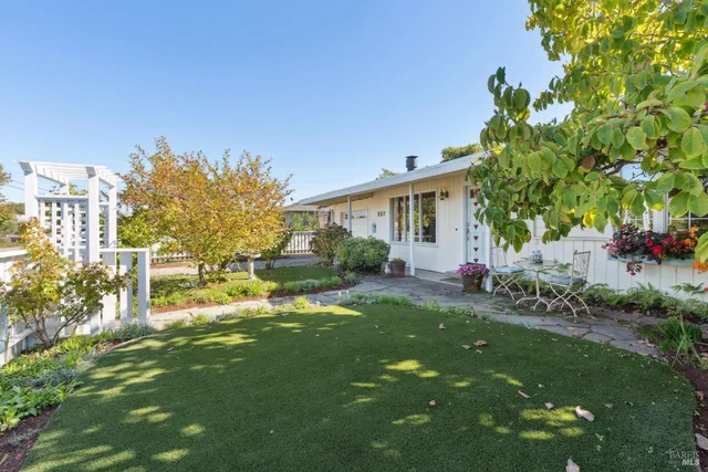 a backyard of a house with table and chairs and potted plants