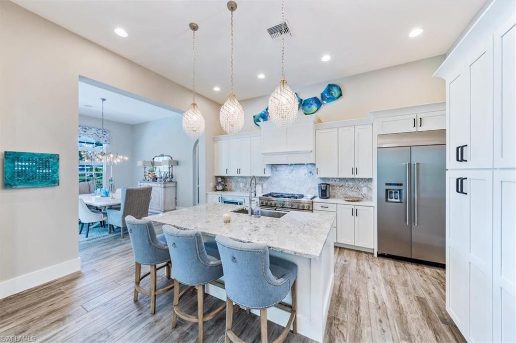 3181 Cullowee Lane Naples, FL 34114 - Photo 12 of 43 a kitchen with a dining table chairs refrigerator and wooden floor