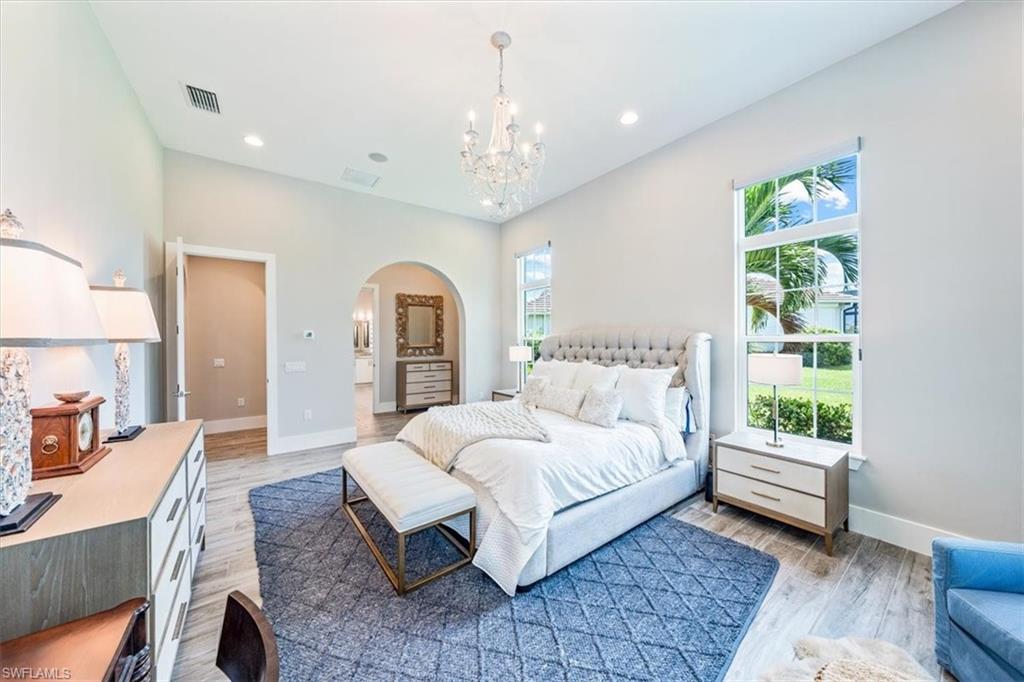 3181 Cullowee Lane Naples, FL 34114 - Photo 19 of 43 a spacious bedroom with a large bed and a chandelier