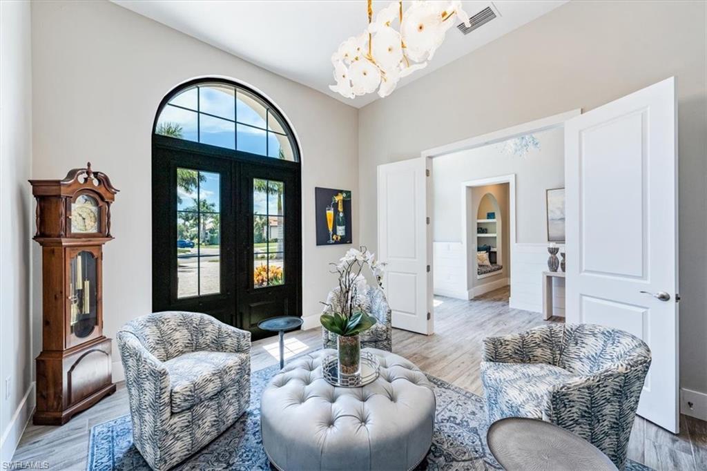 3181 Cullowee Lane Naples, FL 34114 - Photo 4 of 43 a living room with furniture a chandelier and a mirror