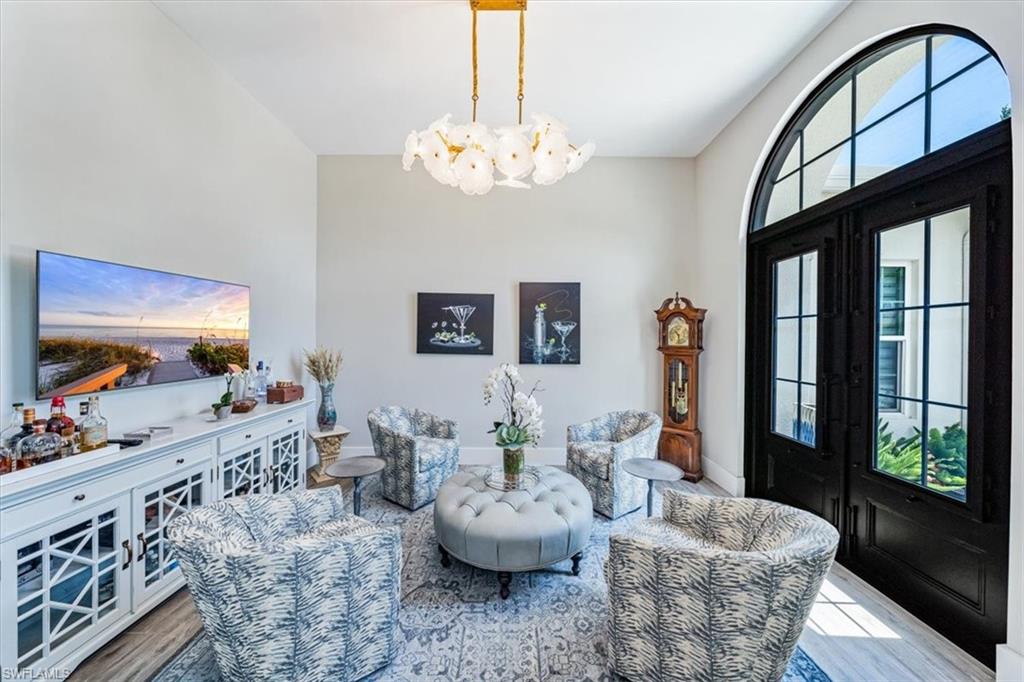 3181 Cullowee Lane Naples, FL 34114 - Photo 5 of 43 a living room with furniture a chandelier and a flat screen tv