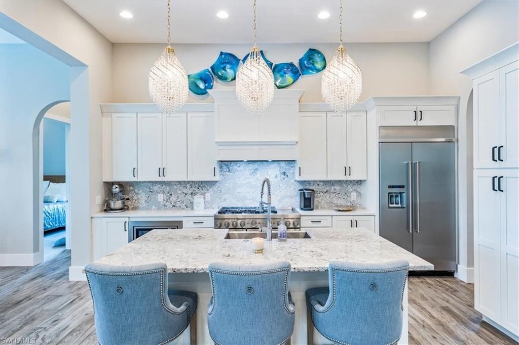 3181 Cullowee Lane Naples, FL 34114 - Photo 10 of 43 a kitchen with stainless steel appliances granite countertop a kitchen island a stove a refrigerator a sink a stove and white cabinets