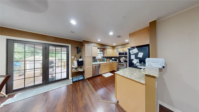 a living room with stainless steel appliances furniture large window and wooden floor