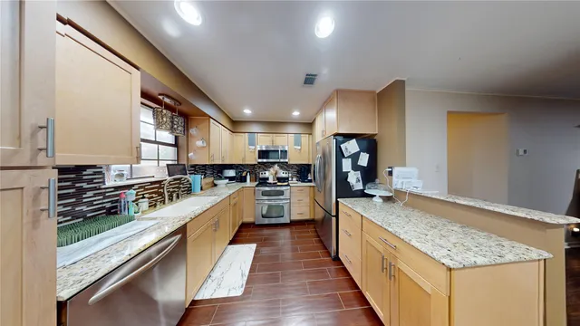 a large kitchen with stainless steel appliances granite countertop lots of counter top space and wooden floor