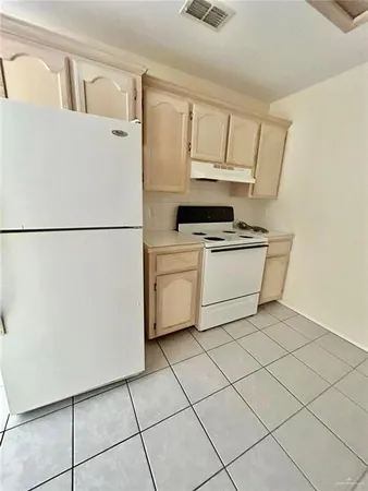 a white refrigerator freezer and a stove sitting inside of a kitchen