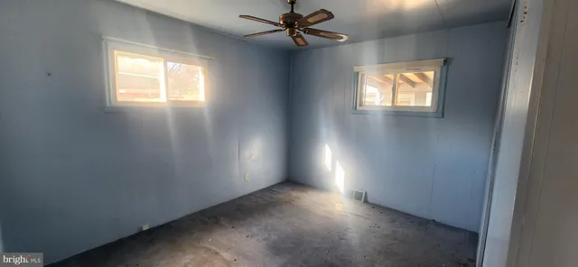 an empty room with windows and fan