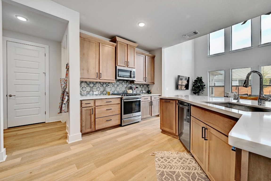 8509 Silverthorne Street Austin, TX 78744 - Photo 11 of 39 a kitchen with stainless steel appliances granite countertop a stove top oven a sink dishwasher and a refrigerator with wooden floor