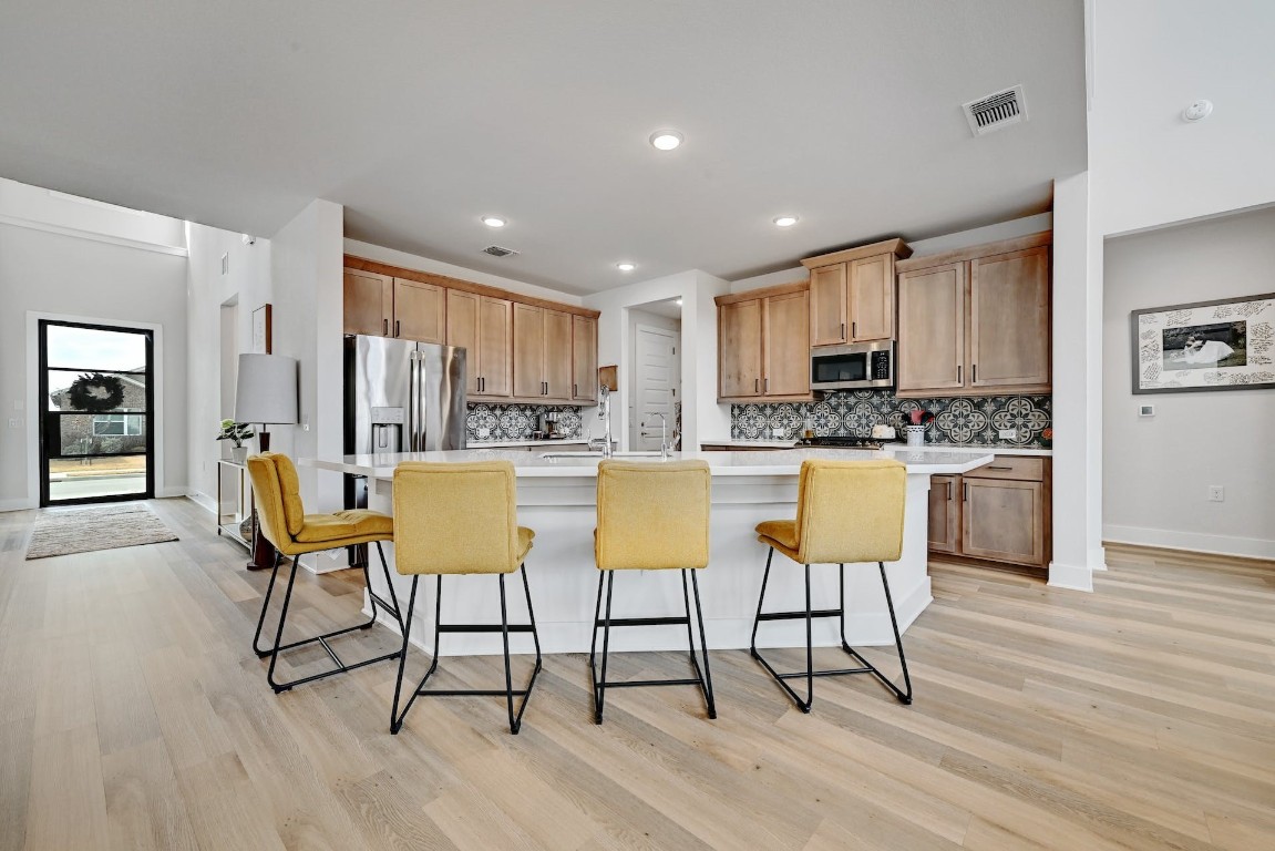 8509 Silverthorne Street Austin, TX 78744 - Photo 8 of 39 a kitchen with stainless steel appliances kitchen island granite countertop wooden floors and white cabinets