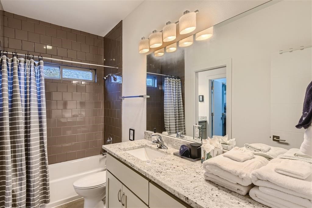 2012 Willow Street, Unit B Austin, TX 78702 - Photo 11 of 15 a bathroom with a granite countertop sink a toilet a mirror a bathtub and shower