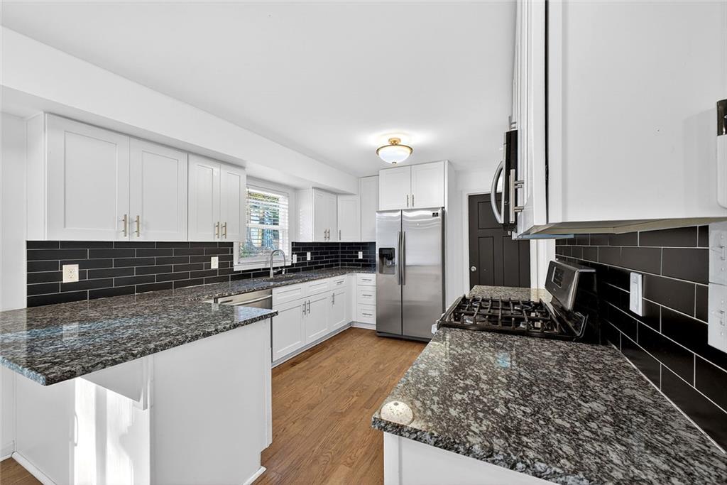1200 Silver Hill Road Stone Mountain, GA 30087 - Photo 6 of 26 a kitchen with stainless steel appliances granite countertop a stove a sink and a refrigerator