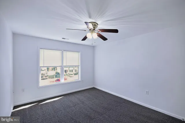 an empty room with windows and ceiling fan